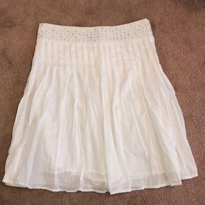 White pleated skirt with embroidered belt.